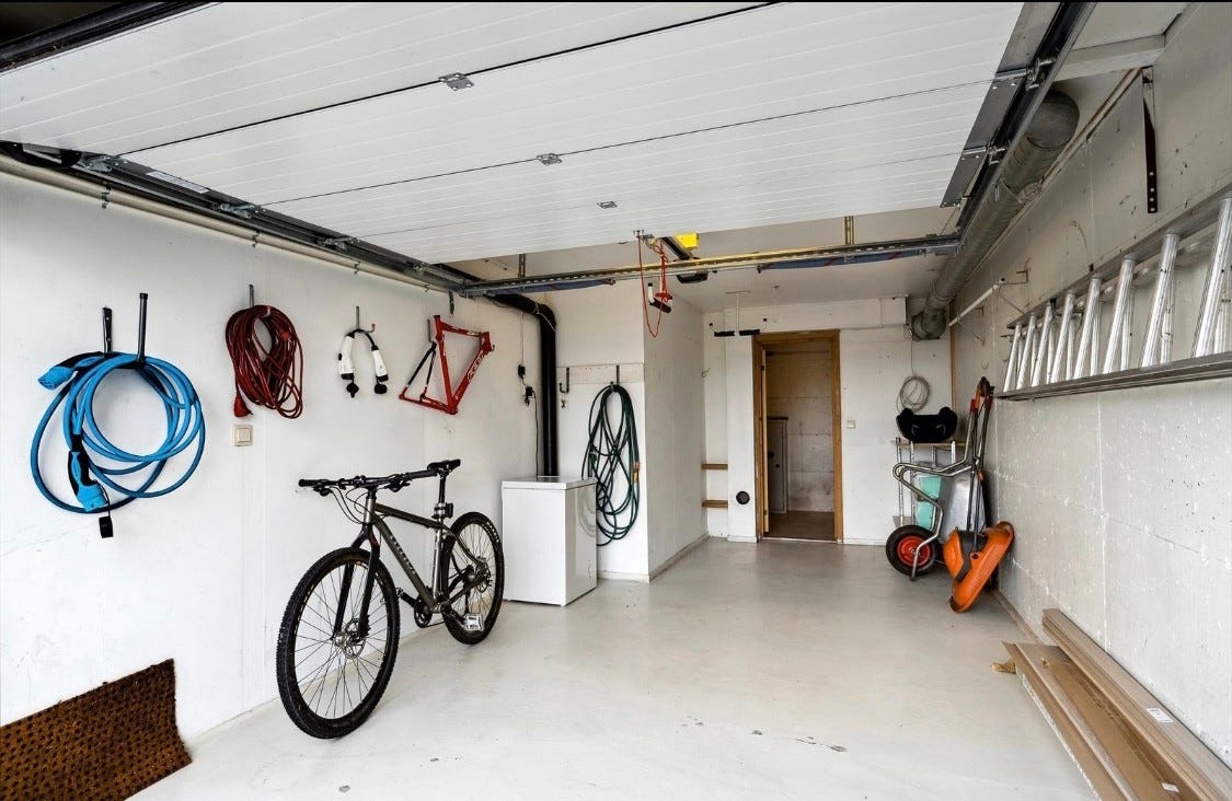 Garasje med port og tilhørende bod.
Det er montert elbil lader på utsiden av garasjen. Galleribilde