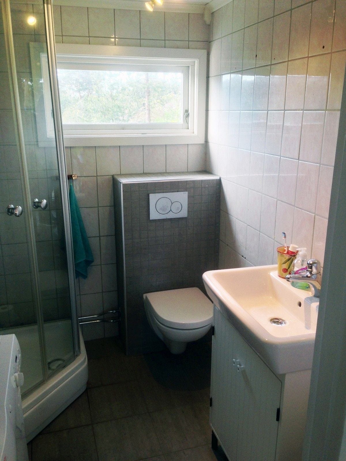 Bad med dusjkabinett, WC og vaskemaskin. Det er et toalett til i hytta. Galleribilde