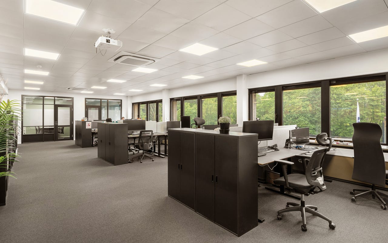 Kontor med store vinduer og utsikt mot grøntarealer – god takhøyde og naturlig dagslys gir trivsel i arbeidshverdagen.