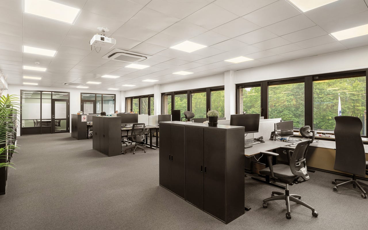 Kontor med store vinduer og utsikt mot grøntarealer – god takhøyde og naturlig dagslys gir trivsel i arbeidshverdagen.