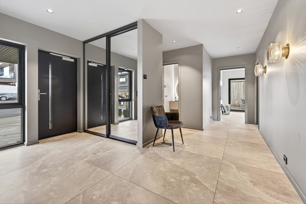 Romslig entré/hall med  smarte garderober og 120x120 cm naturfargede fliser