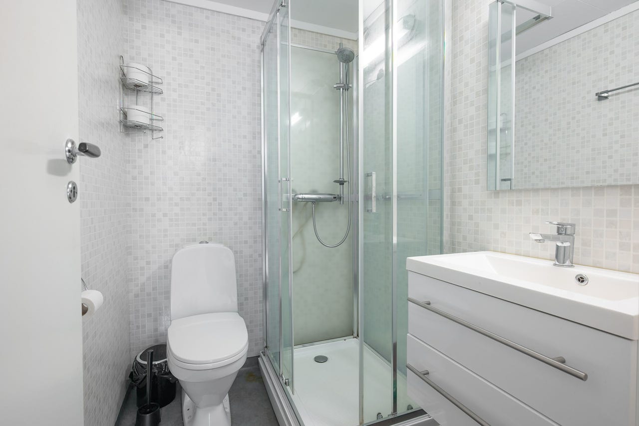 Badet er innredet med dusjkabinett, servansskap med speil og varmekabler i gulv