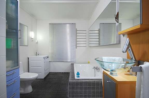 Stort bad med badekar, dusjnisje, opplegg for vaskemaskin og tørketrommel, stort vindu. Galleribilde