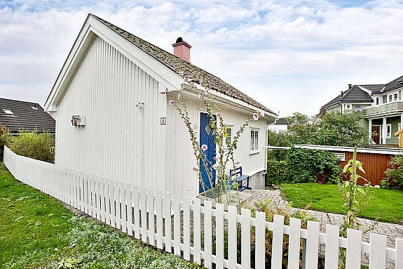 Stakittgjerdet rammer inn den idylliske hagen som er veldig pent beplantet. Her stikker de flotte stokkrosene frem over gjerdet. Galleribilde
