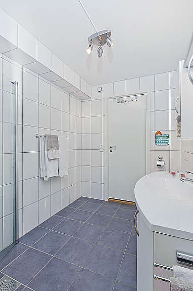 Pent helfliset bad med dusjhjørne, wc, vask og møbler. Galleribilde