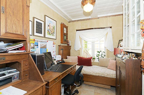 Kontor/ gjesterom med fliselagt gulv. Skap hvor gamle materialer er brukt som dører. Galleribilde