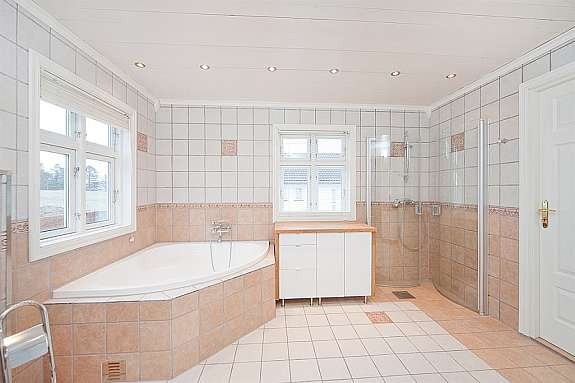 Delikat bad med fliser på gulv og vegger. Badet er utstyrt med hjørnebadekar og dusjhjørne Galleribilde