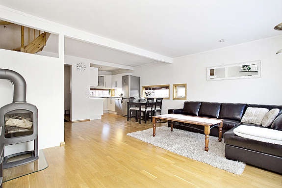 Stue og kjøkken i åpen løsning. Det ligger parkett på gulv, malt tapet på vegg, malte plater i himling. Galleribilde