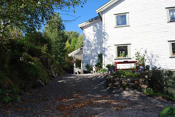 Nytt inngangsparti og gruslagt gangvei.
Varm og lun sitteplass evt dyrkningsplass for tomater ol på støpt platting i hushjørnet. Galleribilde