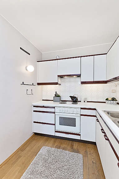 Kjøkkeninnredning med glatte fronter. Laminat benkeplate og fliser over benk. Galleribilde