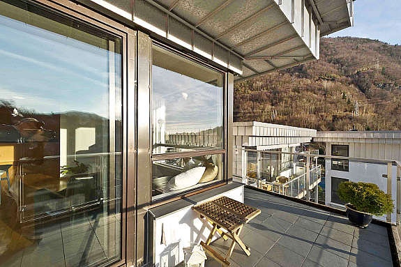 Terrassen har glassrekkverk og tiltalende fliser på gulvet. Galleribilde