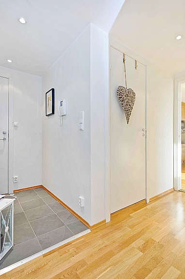 Gangen er malt i en lys fargepalett. Betjeningspanel til porttelefon med bildeoverføring er plassert på veggen i gangen. Galleribilde