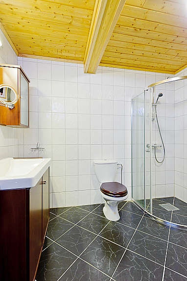 Badet i kjellerleiligheten inneholder fliser på gulv, dusjhjørne, toalett, servant og møbler. Gulvvarme. Galleribilde