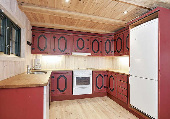 Innredning med malte fronter, benkeplate i heltre med nedfelt kum. Ventilator over komfyrplass og opplegg for oppvaskemaskin. Galleribilde