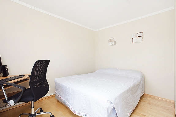 Flott og romslig soverom med parkett på gulv og lyse flater Galleribilde