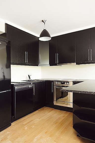 Stilfult kjøkken med moderne slett, sort innredning. På kjøkkenet er det god skap- og benkeplass. Galleribilde