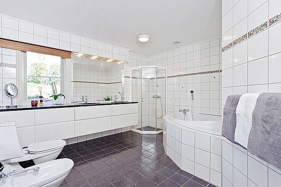 Romslig bad i 1. etasje med Versace designfliser på veggene samt innfliset badekar og praktisk dusjhjørne. Galleribilde