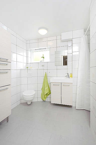 Hvitt og delikat baderom med fliser på vegger og gulv. Galleribilde