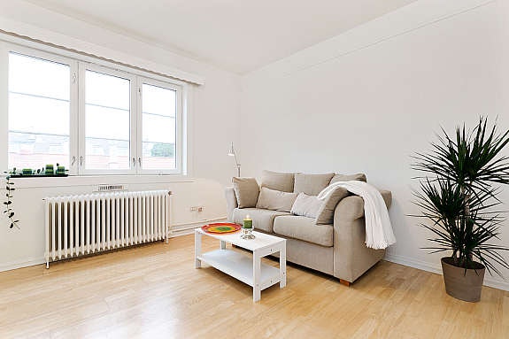 Lysmalte vegger og laminatgulv setter et hyggelig preg på oppholdsrommet. Galleribilde