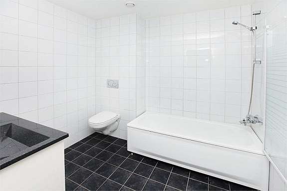 Lekkert, flislagt bad m/badekar og vegghengt wc Galleribilde