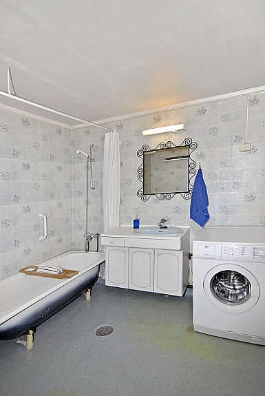 Baderom med badekar, servant, wc og opplegg for vaskemaskin. Galleribilde