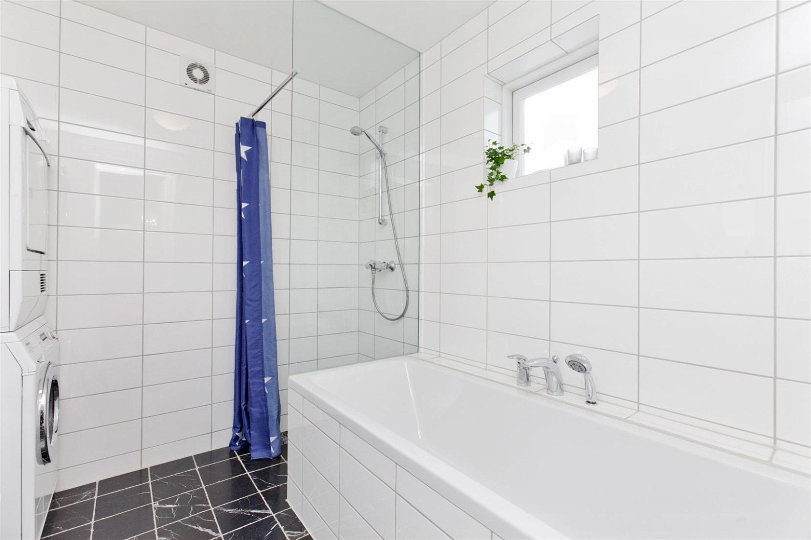 Badet inneholder badekar, dusjhjørne, opplegg og plass til vaskemaskin/søyle, servant med underskap og speil over og vegghengt wc. Galleribilde