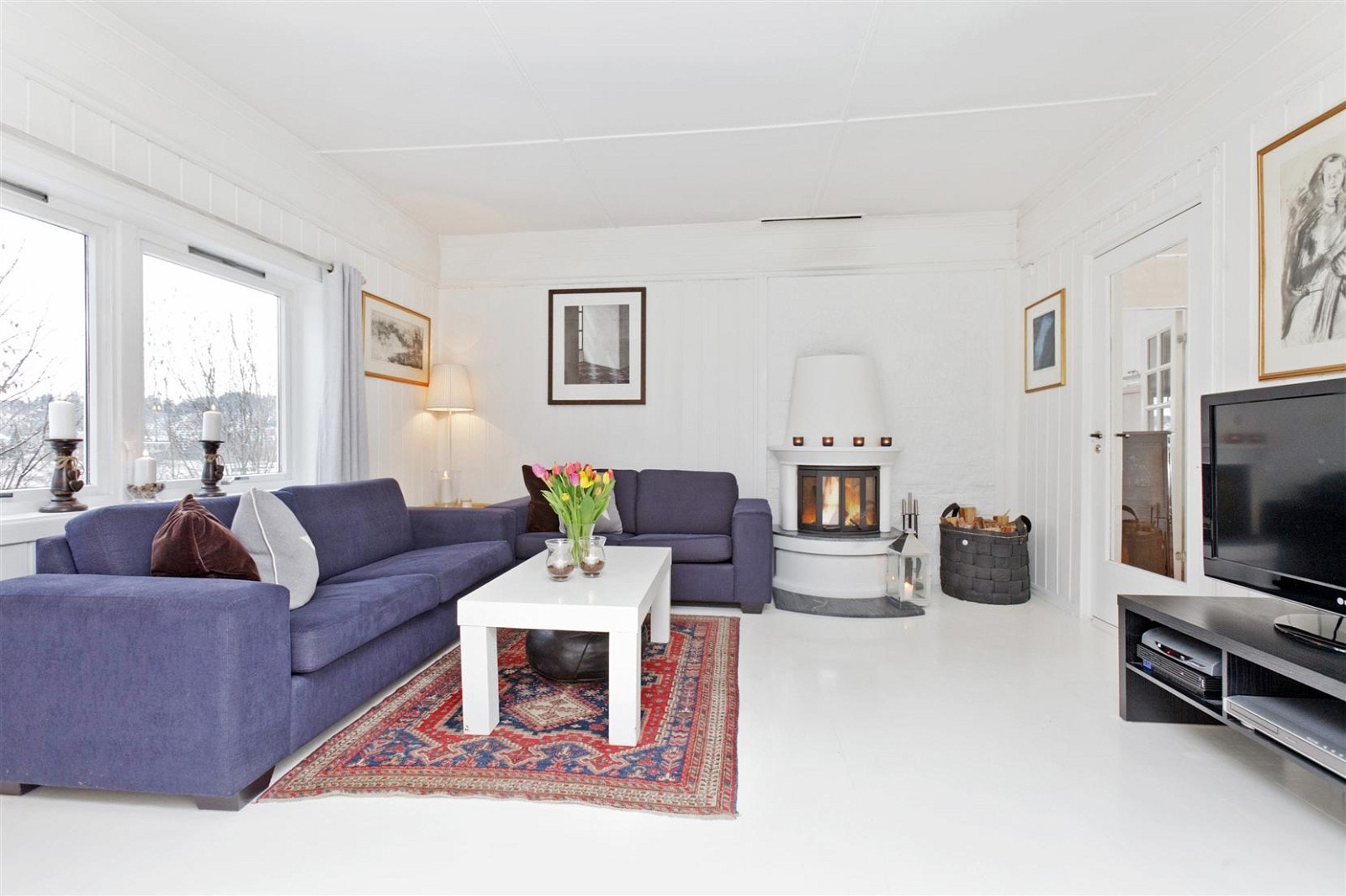 Stue med peis.
Lyse farver på vegger og på gulv, ekstra god takhøyde kombinert med store vindusflater gir en luftig og behagelig romfølelse. Galleribilde