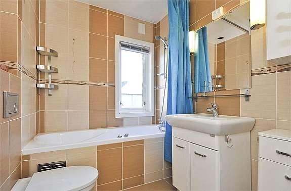 Fliselagt baderom med boblebad/dusj og vegghengt toalett Galleribilde