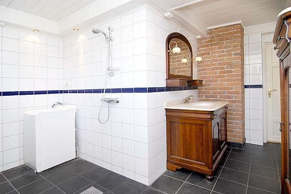 Tiltalende og moderne bad med håndlaget spansk innredning i mahogni og marmor benkeplate. Galleribilde