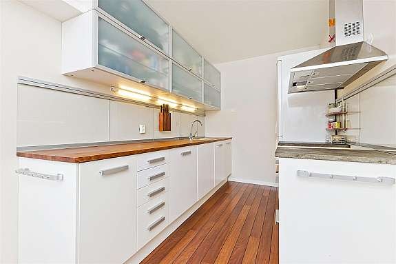 Meget pent kjøkken med hvite glatte fronter. Heltre benkeplate, samt støpt benkeplate ved komfyr. Glass over benk. Galleribilde