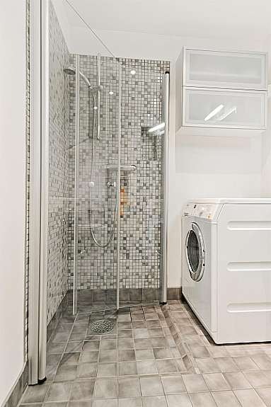 Dusj med mosaikkfliser og innsvingbare dusjvegger i herdet glass. Plass til vaskemaskin. Galleribilde