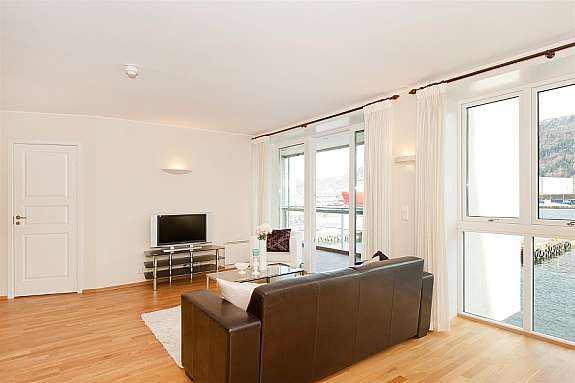 Stue og kjøkken har store vindusflater fra gulv til tak. Noe som gir en behagelig nærhet til sjøen og gjør den flotte utsikten lett tilgjengelig. Galleribilde