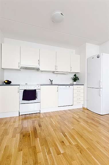 Tidløs og moderne kjøkken i lyse glatt utførsel med opplegg for vaskemaskin og god oppbevaringsplass. Galleribilde