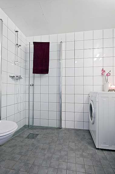 Flislagt bad fra byggeåret 2005, med vegghengt klosett, dusjhørne med glassdører og opplegg for vaskemaskin. Galleribilde
