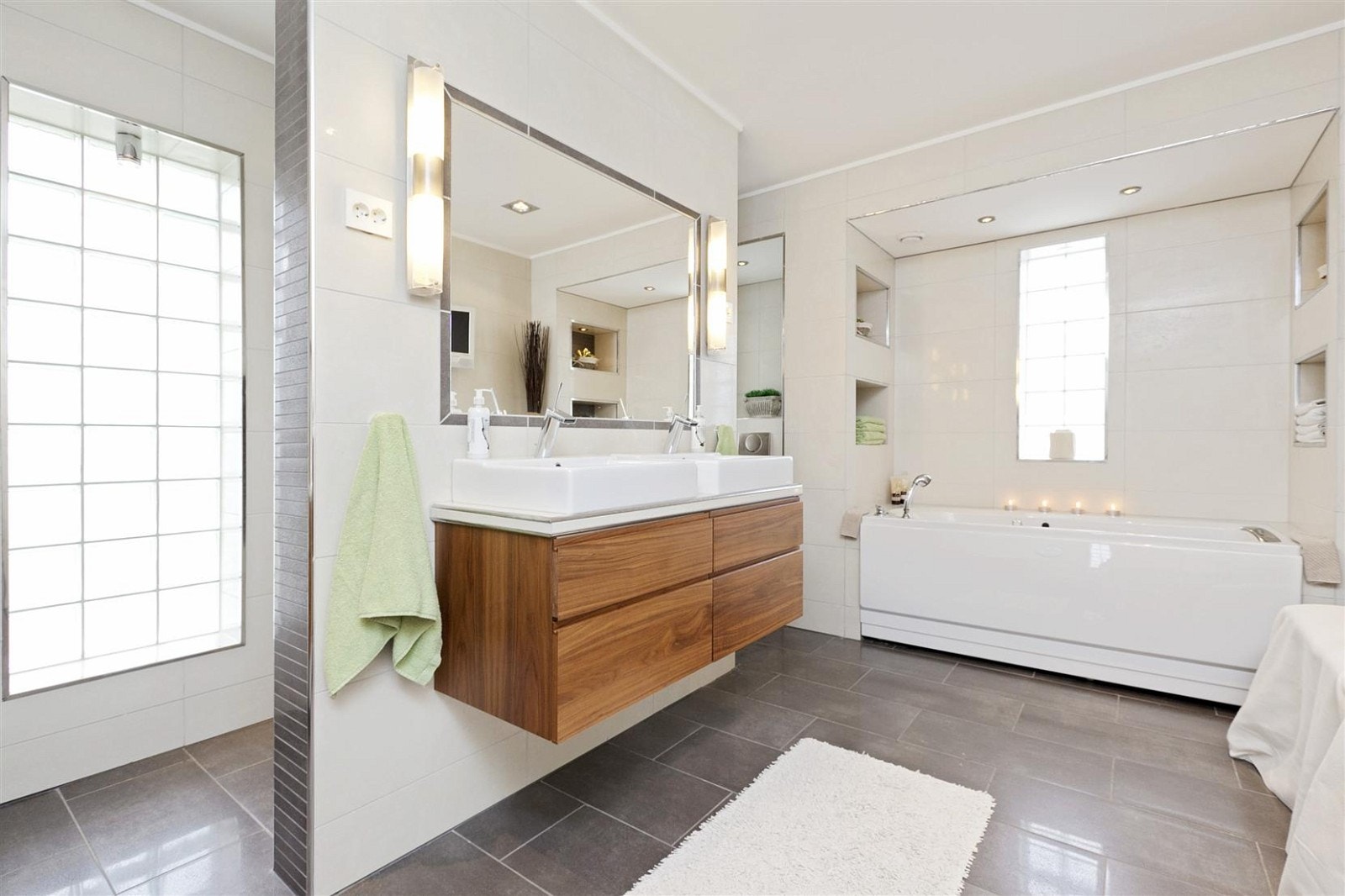 Flislagt og romslig bad som inngår som en del av "masterbedroom"-avdelingen. Kvalsvik innredning med god skapplass, delvis innmurt massasjebadekar med nisjebelysning, wc, vegg hengt TV, og egen dusjnisje med Rainshower-system fra Grohe. Galleribilde