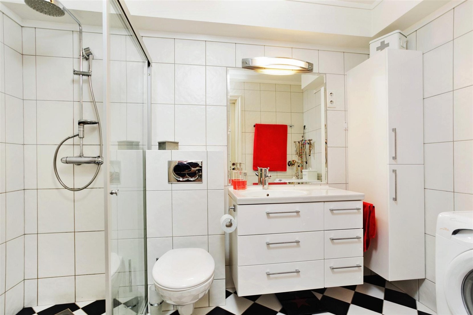 Lekkert flislagt bad med vegghengt wc, dusjhjørne, servant i innredning og opplegg til vaskemaskin Galleribilde