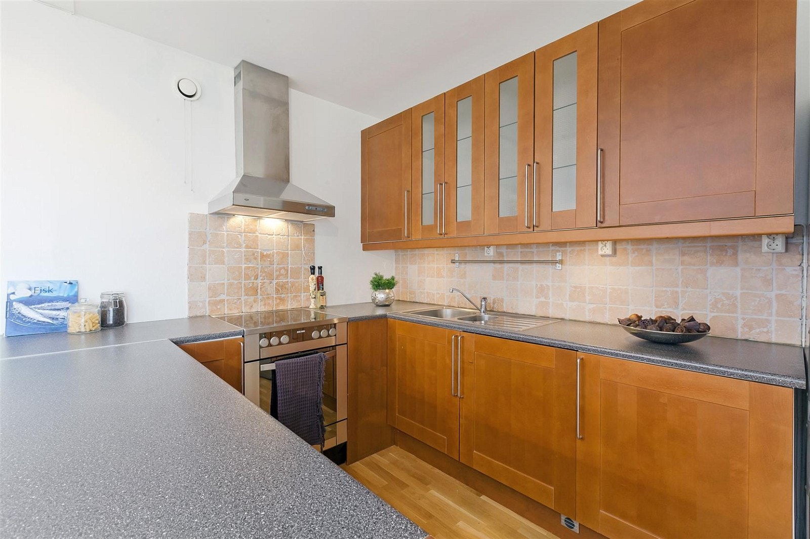 Pen kjøkkeninnredning med kirsebærfargede fronter og vitrinskap. Galleribilde