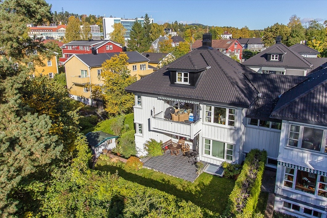 Fliselagt terrasse utenfor stuen, plen og uthus Galleribilde