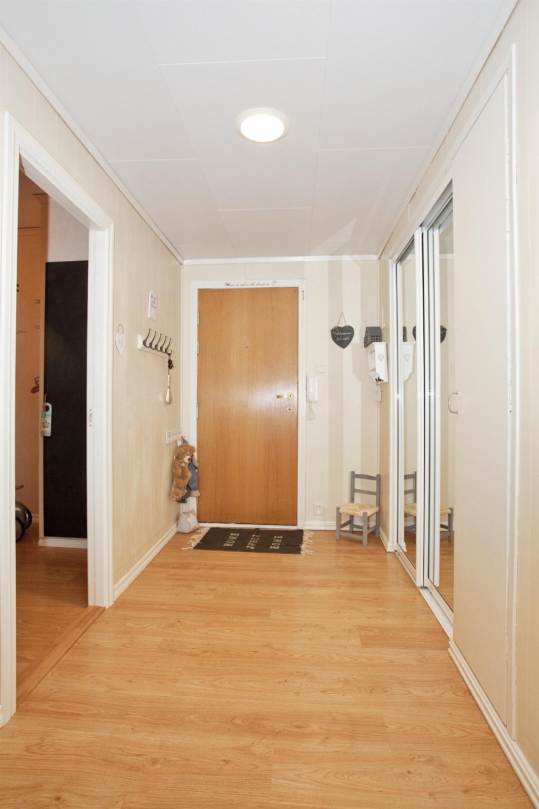 Rektangulær og lysmalt gang med garderobeplass samt vegghengt betjeningspanel til porttelefon. Galleribilde