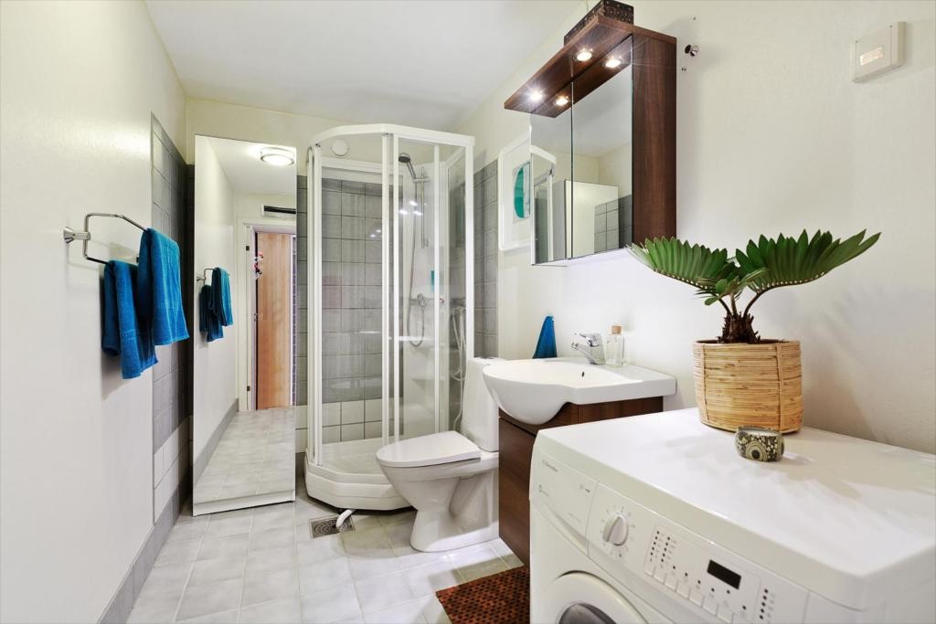 Stort bad med dusjkabinett og opplegg til vaskemaskin Galleribilde