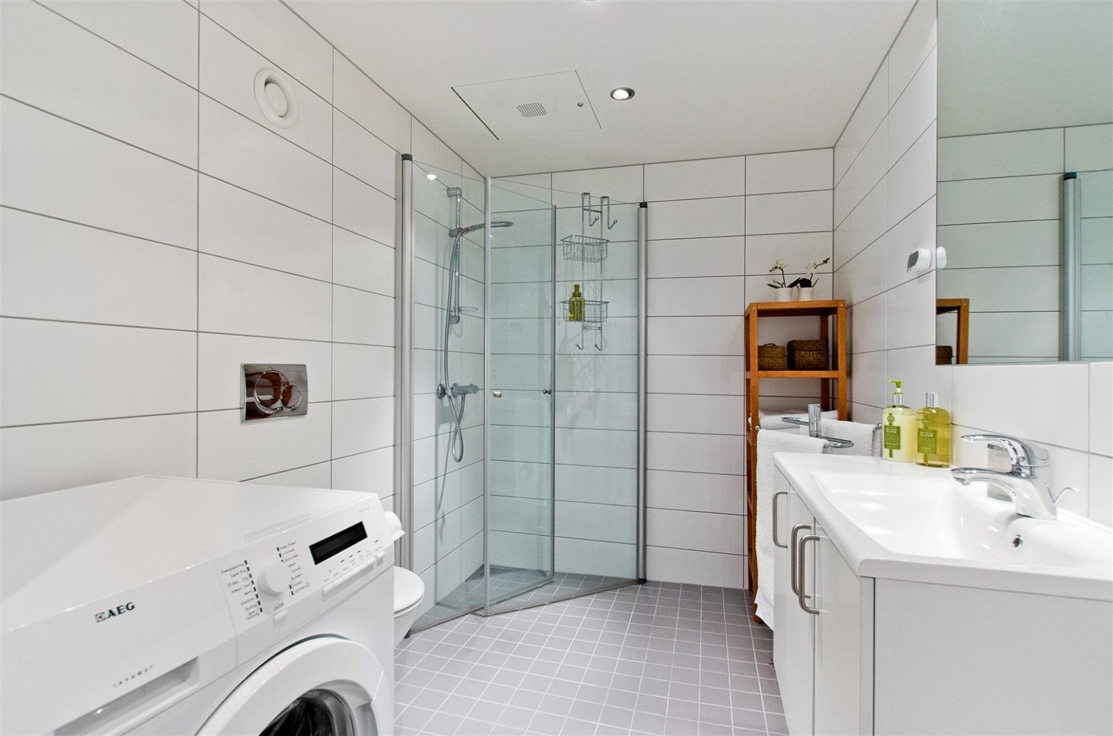 Infellbare dusjdører i glass og opplegg for vaskemaskin. Downlights i himling og termostatstyrte varmekabler i gulv. Galleribilde