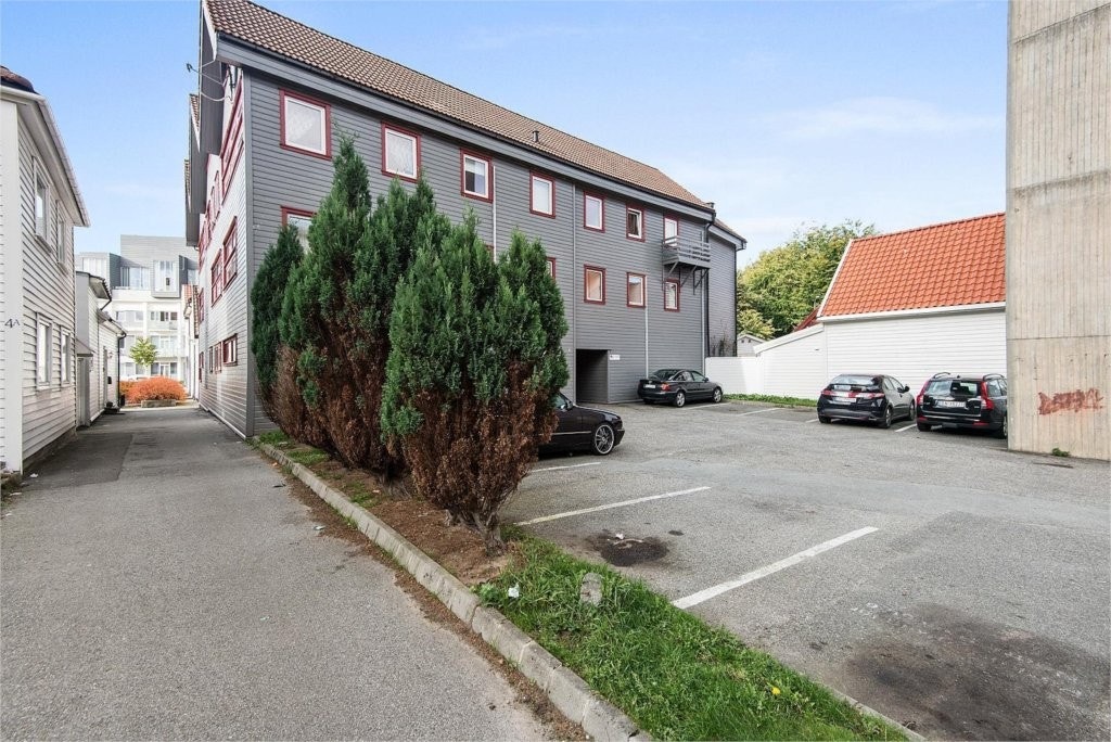 Parkeringsplass og fasade på bygg sett fra siden Galleribilde