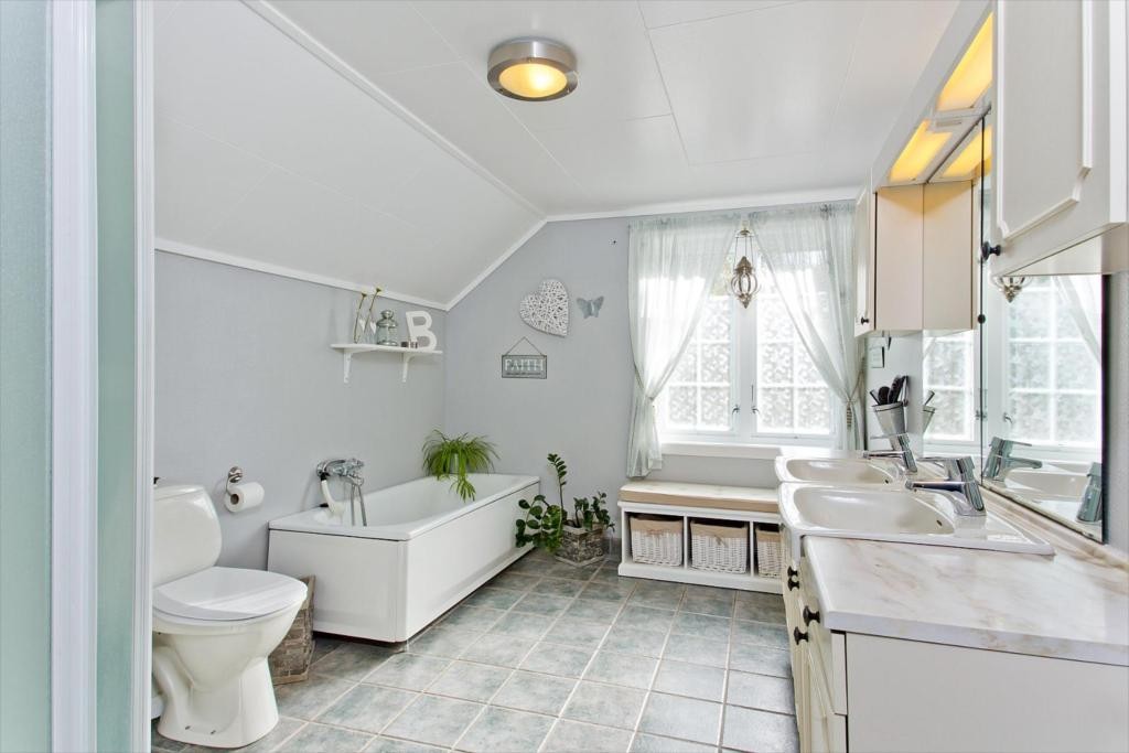 Bad med wc, badekar, dusjkabinett, innredning med dobbel vask og varmekabler. Galleribilde