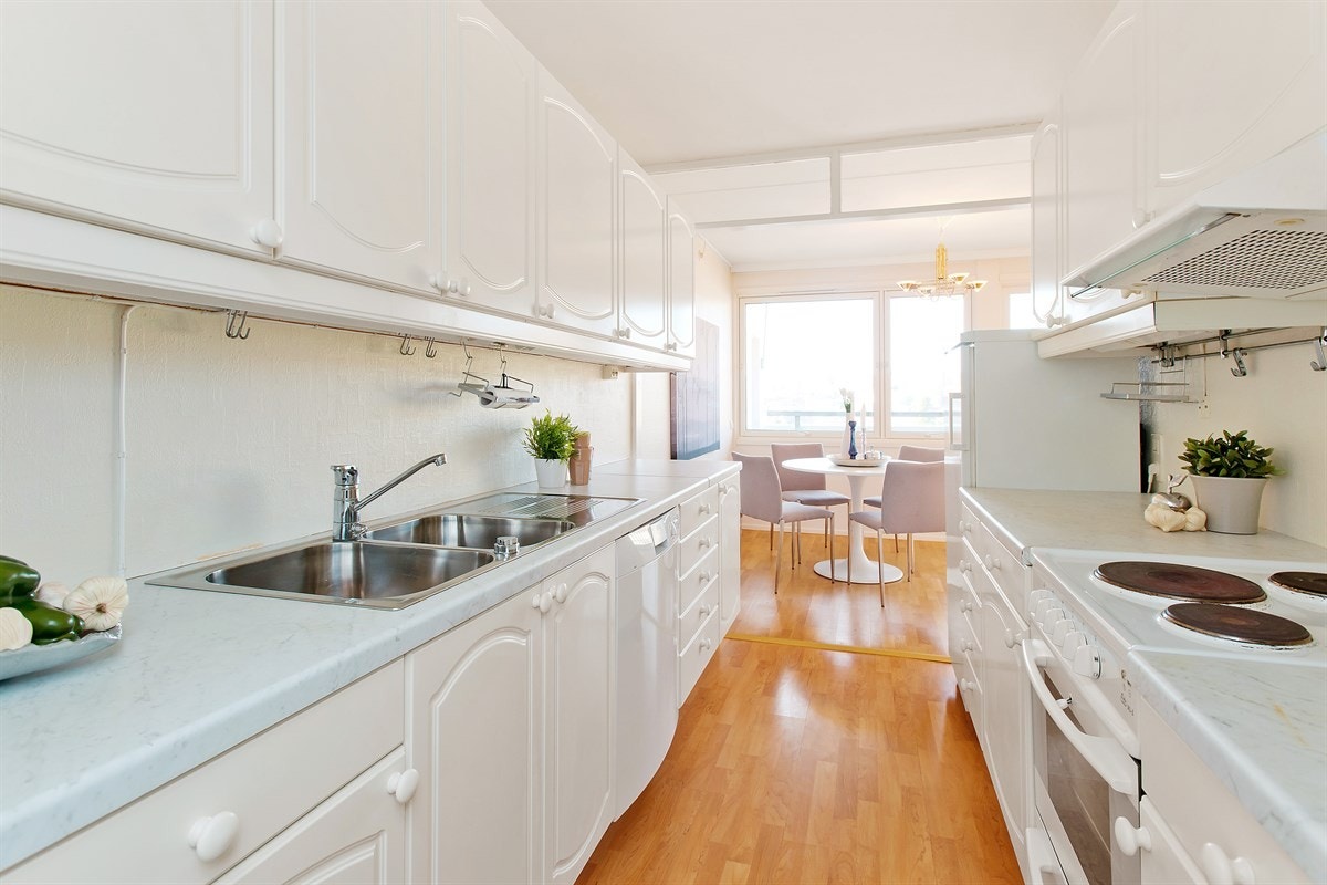 Lyst og praktisk kjøkken med mye skapplass. Inngang til vaskerom fra kjøkkenet Galleribilde