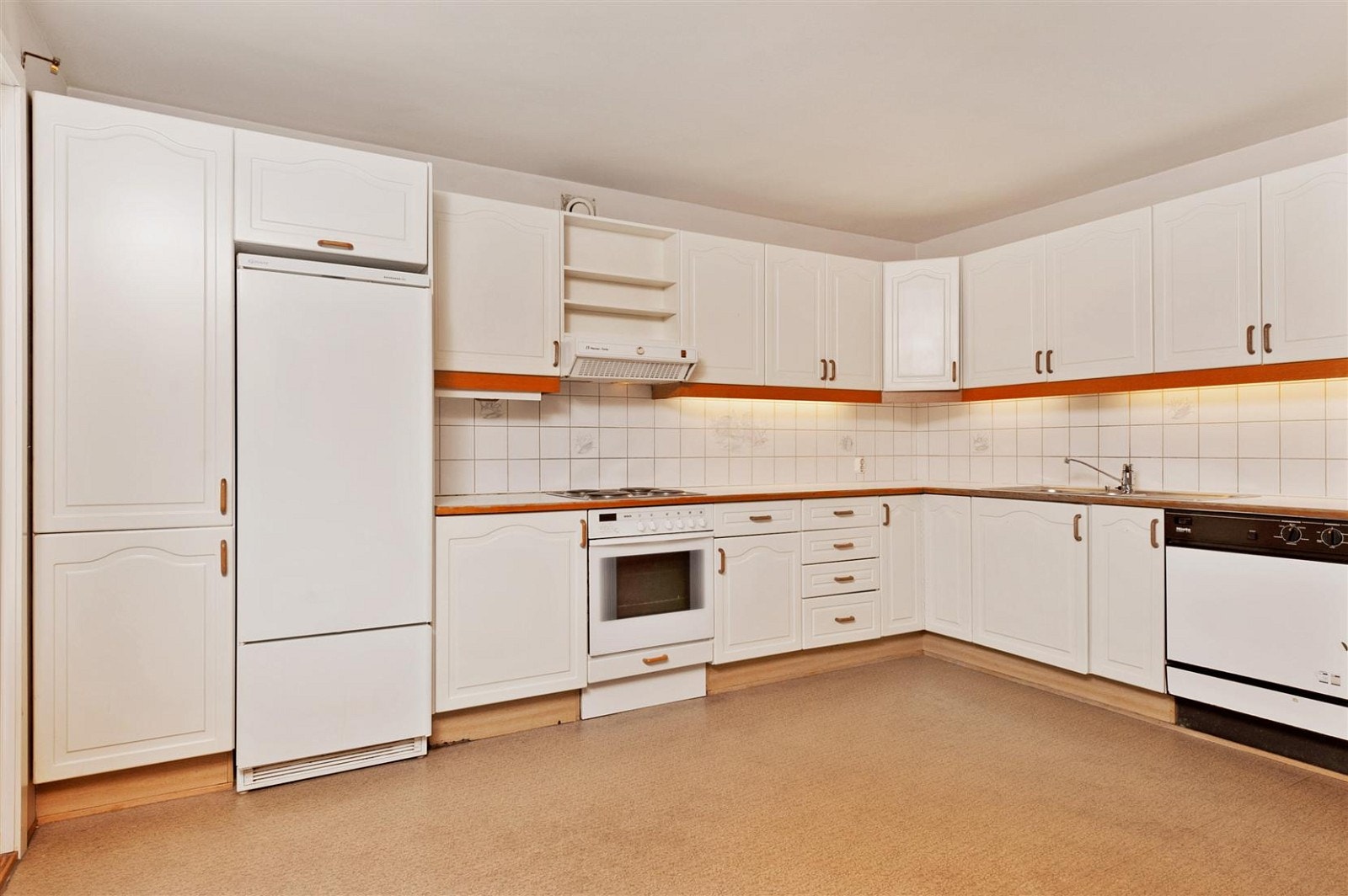 Kjøkkenet har svært mye skapplass, med fliser mellom benkeplate og overskap. Komfyren er integrert og oppvaskmaskin er på plass under kjøkkenbenk. Galleribilde