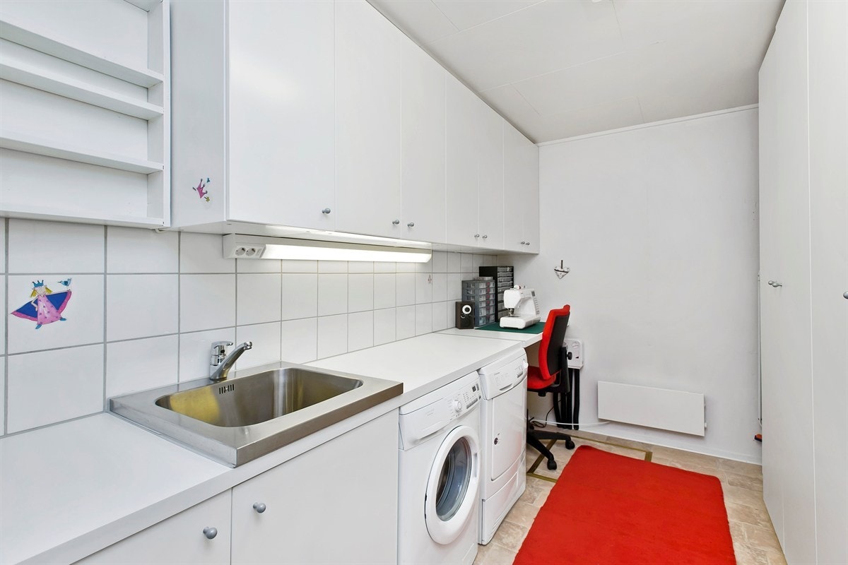 Praktisk vaskerom med gode lagringsmuligheter og opplegg for vaskemaskin. Galleribilde