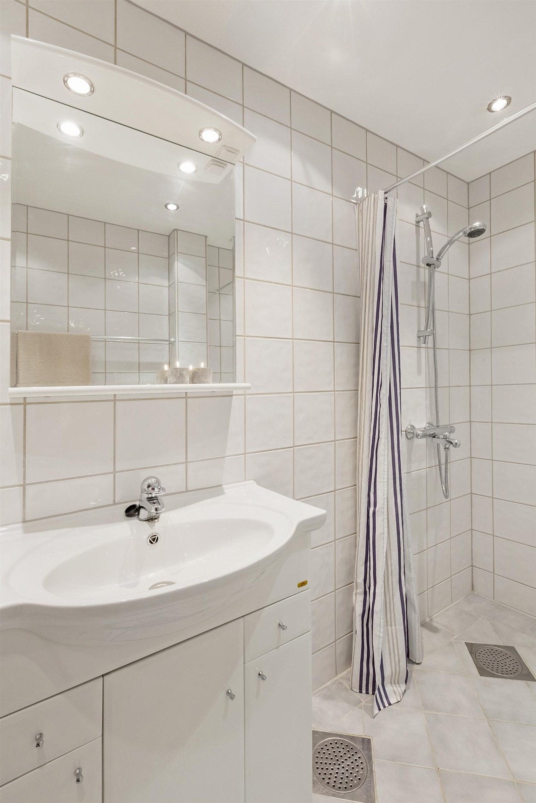 Baderomsinnreding med servant og underskap, dusj, skapplass, opplegg og plass til vaskemaskin. Galleribilde