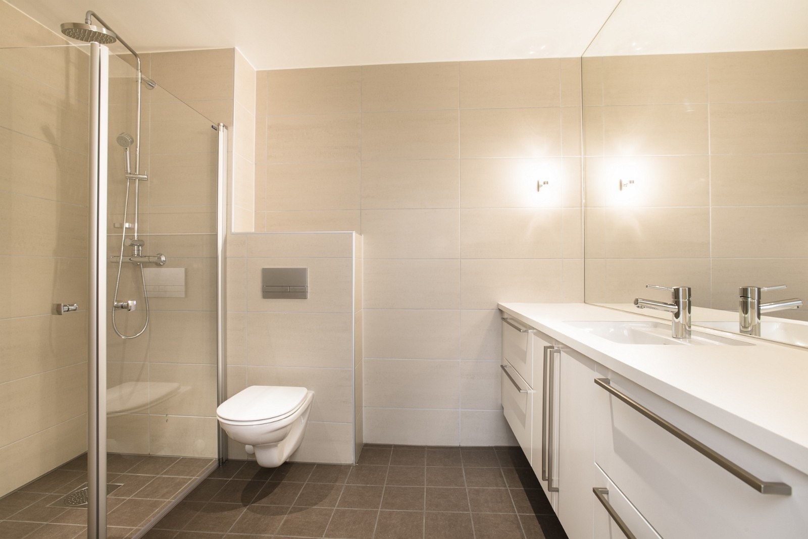 Bad med servant, fliser, vegghengt toalett og dusj med glassdør. Galleribilde