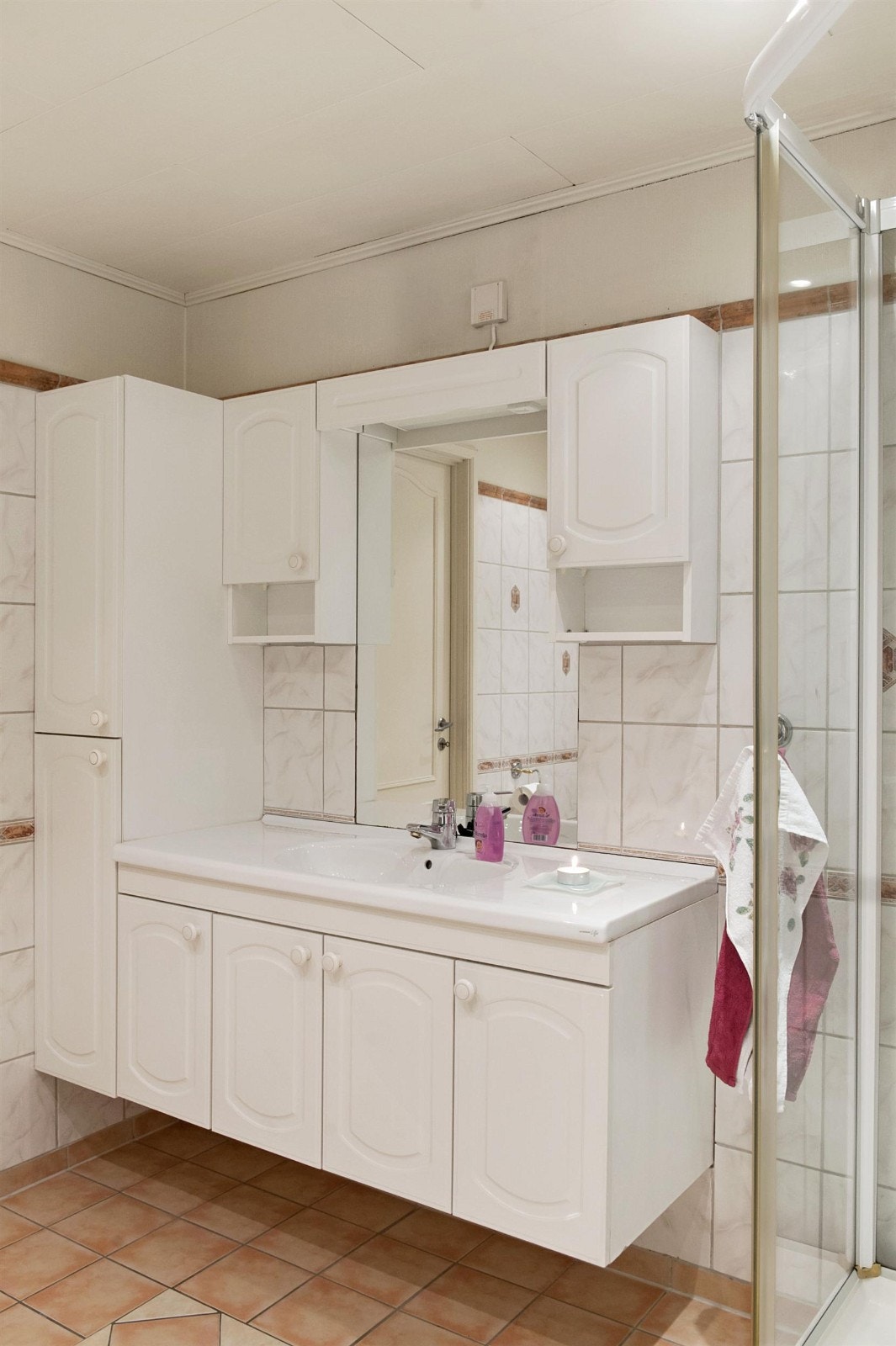 Flislagt bad med varmekabler, downlights, hvit WC, heldekkende servant, stort hjørneboblekar og dusjkabinett. Galleribilde