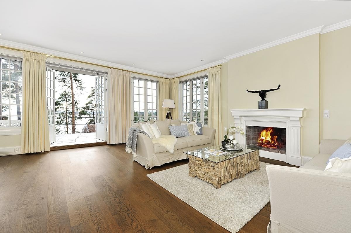 Lys stue med vakker engelsk peis og utgang til solrik terrasse Galleribilde